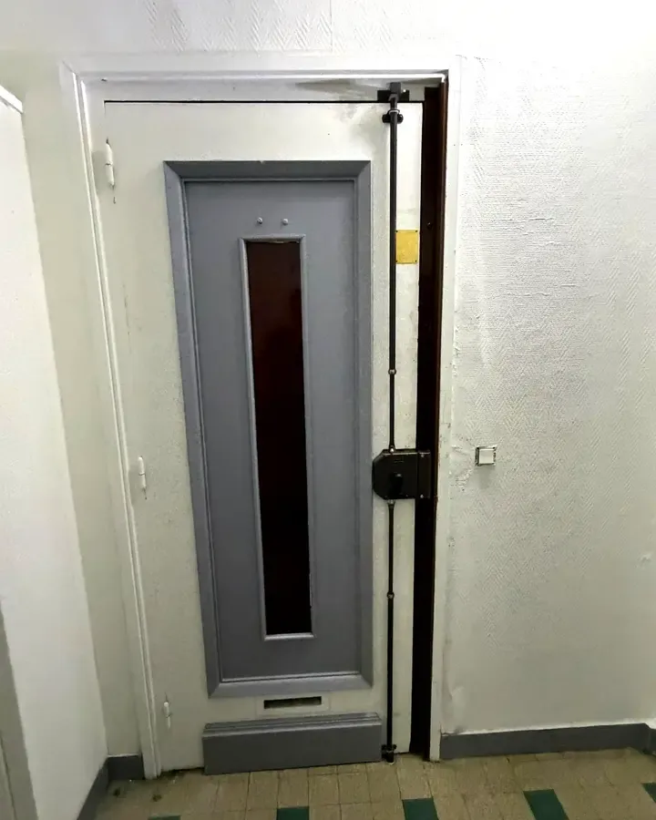 Porte paliere grise d'un immeuble avec imposte vitree etroite