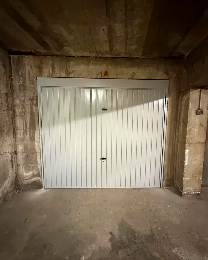 Porte de garage basculante blanche dans un sous-sol en beton