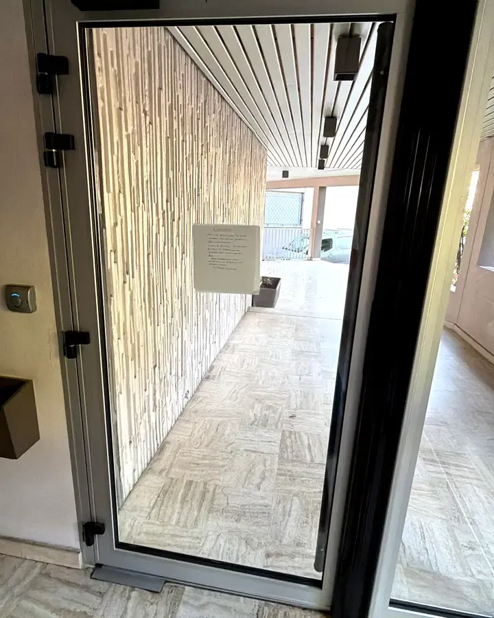 Porte vitree aluminium avec ferme-porte dans un couloir d'immeuble